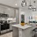Open-plan kitchen with cabinets, modern light fixtures, island sink, and up-to-date microwave, oven with stovetop, and fridge